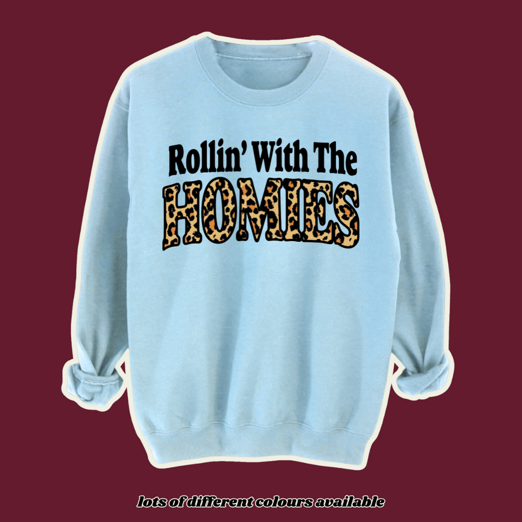 90s-inspired light blue sweatshirt with 'Rollin’ With The Homies' slogan in bold black and leopard print lettering. Retro oversized jumper, vintage hip-hop fashion, Y2K streetwear style