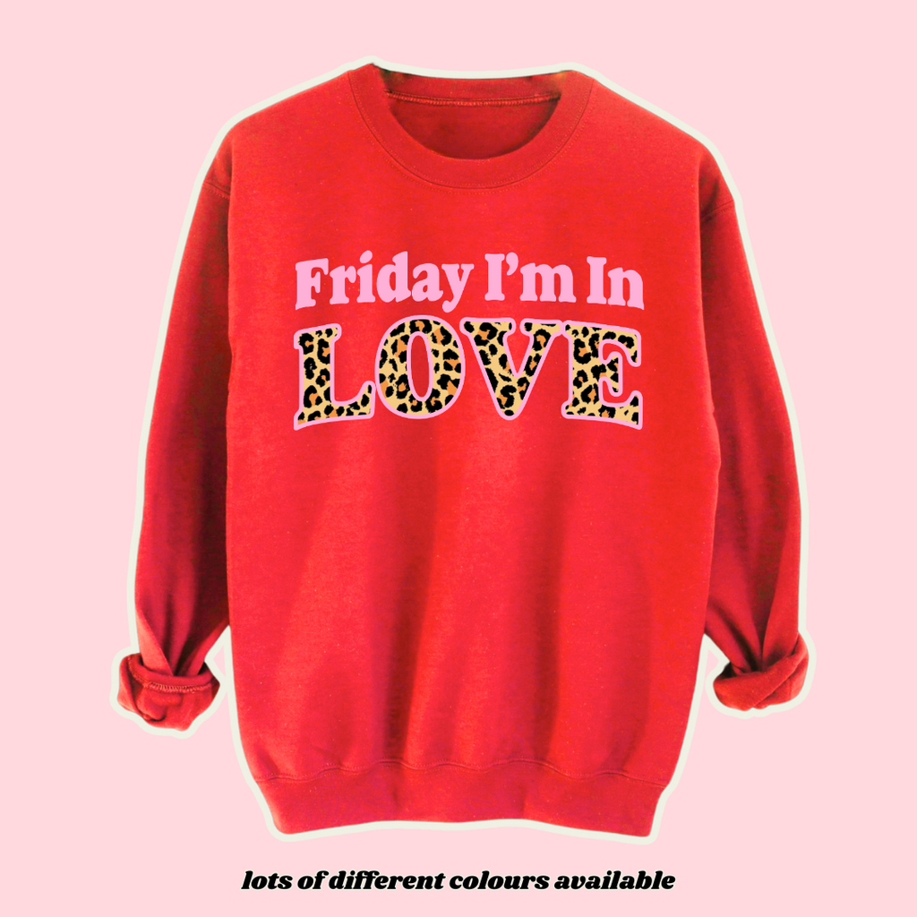 Red fleece-lined sweatshirt with 'Friday I’m In Love' slogan in bold leopard print lettering. Stylish, unisex oversized jumper, perfect for casual wear, streetwear, and loungewear. Customisable with different colours and prints, made to order for a unique personalised look