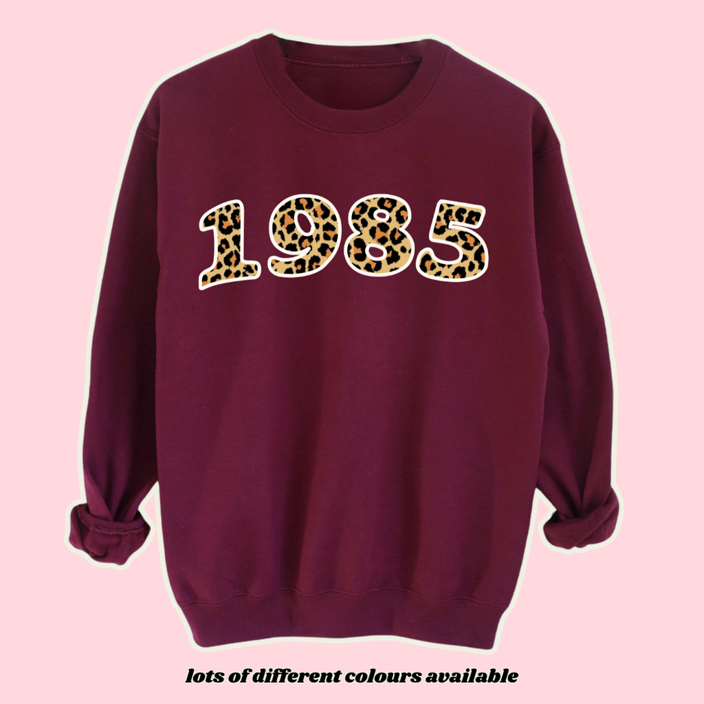 Retro birth year sweatshirt with leopard print numbers on a burgundy fleece-lined jumper. Vintage 80s and 90s style personalised birthday sweatshirt, perfect for milestone birthdays like 30th, 40th, or 50th. Unisex oversized fit, customisable colours and text. Trendy throwback fashion gift idea