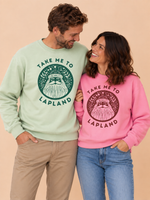 Load image into Gallery viewer, A man and a woman standing side by side wearing matching crewneck sweatshirts with a forest graphic and the text 'TAKE ME TO LAPLAND'. The man's sweatshirt is light sage green, and the woman's is pink.
