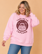 Load image into Gallery viewer, A woman wearing a light pink crewneck sweatshirt with a dark burgundy graphic of a bearded Santa Claus and the text 'TAKE ME TO LAPLAND'.
