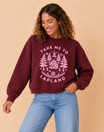 Load image into Gallery viewer, A woman wearing a maroon crewneck sweatshirt with a pink graphic that reads 'TAKE ME TO LAPLAND' and shows blue jeans, posing against a solid beige background.
